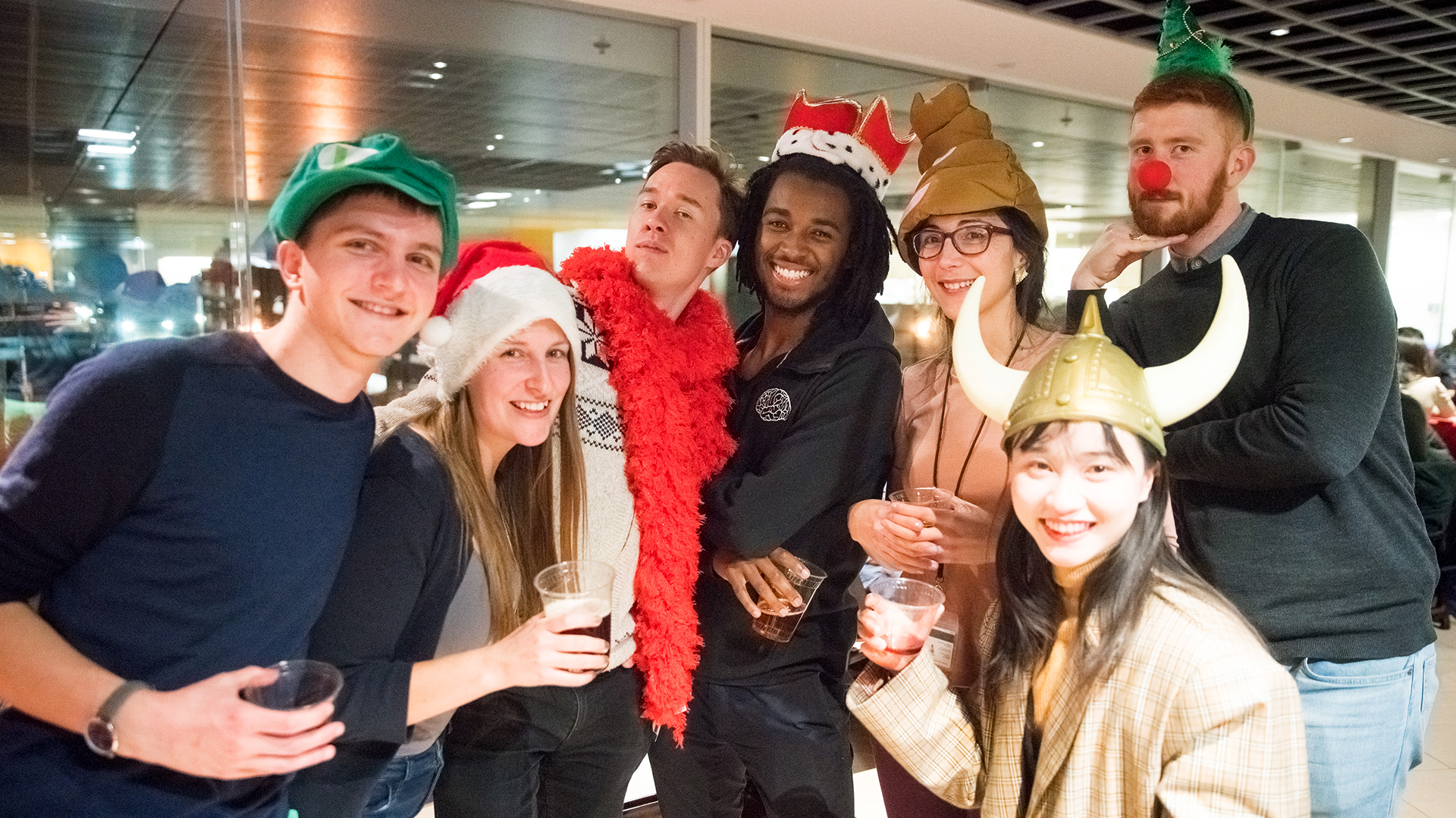 Seven people in funny hats at a holiday party