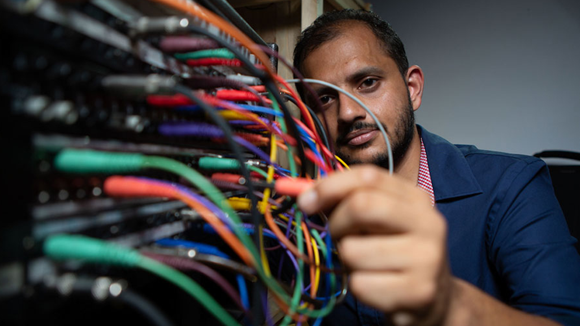 postdoctoral fellow Arghya Mukherjee handles wires on a rack of computers