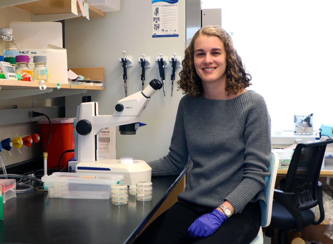 Talya Kramer seated next to a microscope